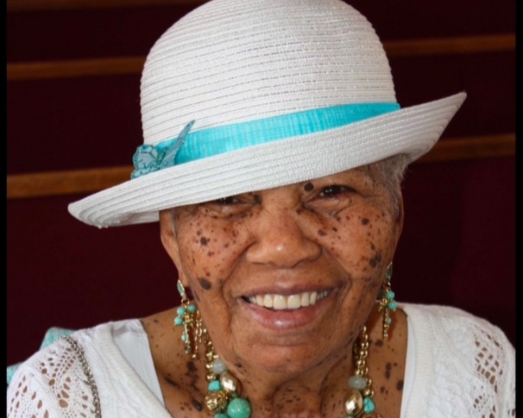 Louise Melba Mercer smiling in a white sun hat and turquoise jewelry