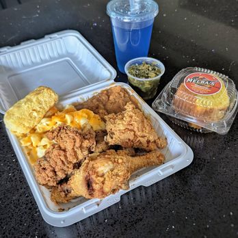 To-go box with fried chicken, mac and cheese, greens, cornbread and peach cobbler
